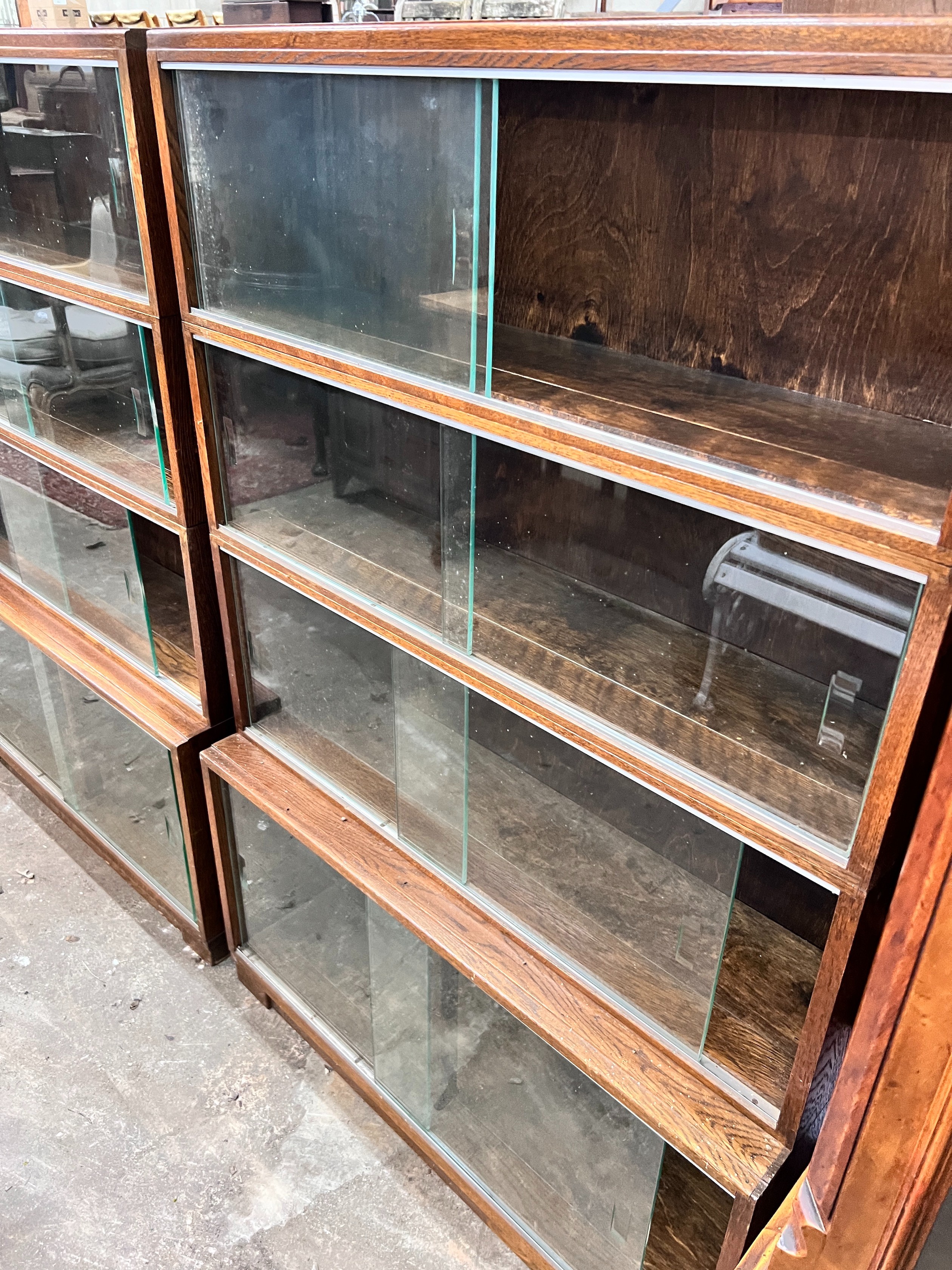 Five 1960's oak Minty bookcases comprising two four section, one three section, and a near pair of two section bookcases, widest 89cm, depth 30cm, height 135cm *Please note the sale commences at 9am.